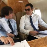 Con gafas de sol y un asesor dentro del avión, como Kennedy.