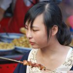 Una joven comiendo en un puesto de comida callejera en Pekín. J.M. PAGADOR