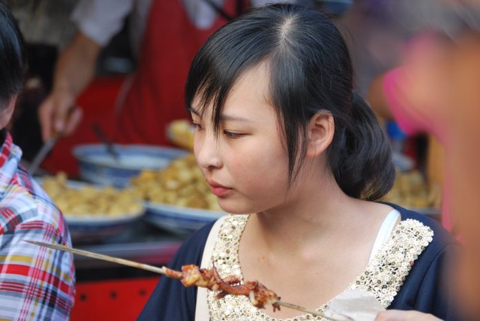 Una joven comiendo en un puesto de comida callejera en Pekín. J.M. PAGADOR